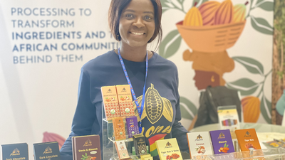 Ghanaian woman stands behind table of chocolate bars package in traditional motifs