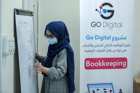 A young woman attending a Go Digital training is writing on a board