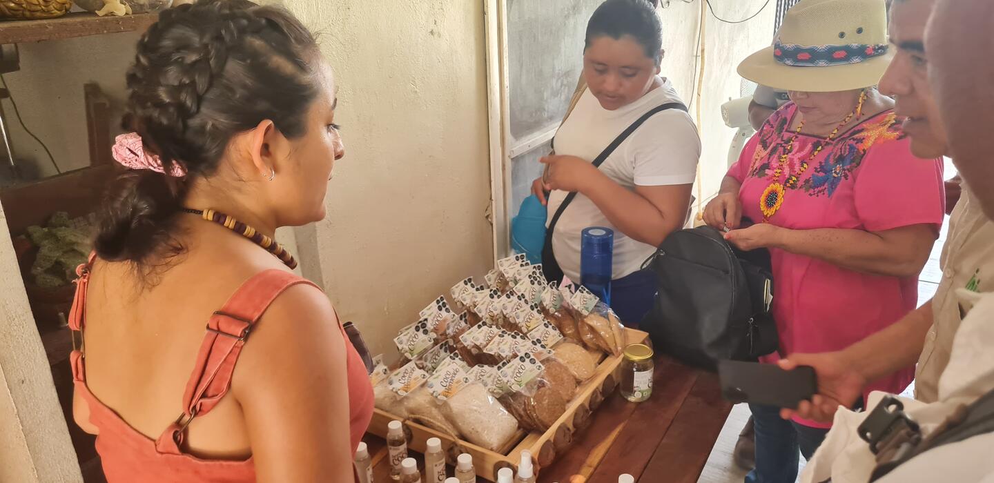 Un grupo de mujeres muestran productos de coco a los turistas.