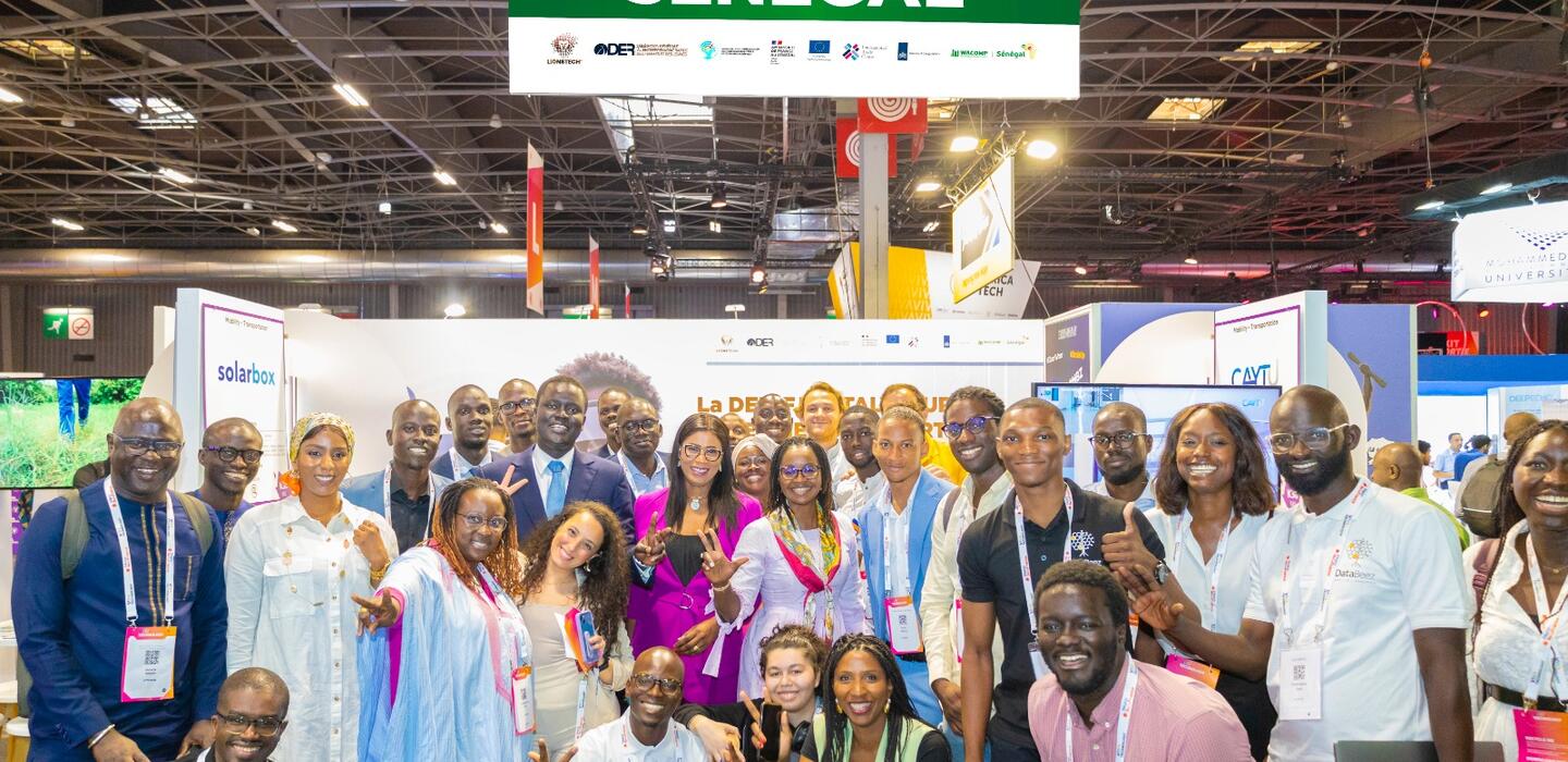 Un groupe d'entrepreneurs technologiques africains pose sous la bannière du pavillon sénégalais au salon VivaTech de Paris.