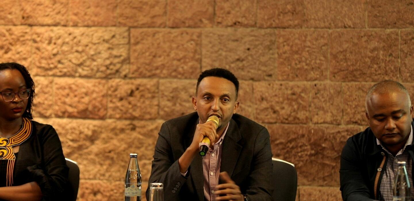 Ethiopian man speaks into microphone on panel 