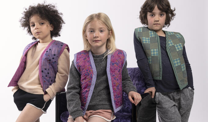 Three children model patchwork clothing made from upcycled materials