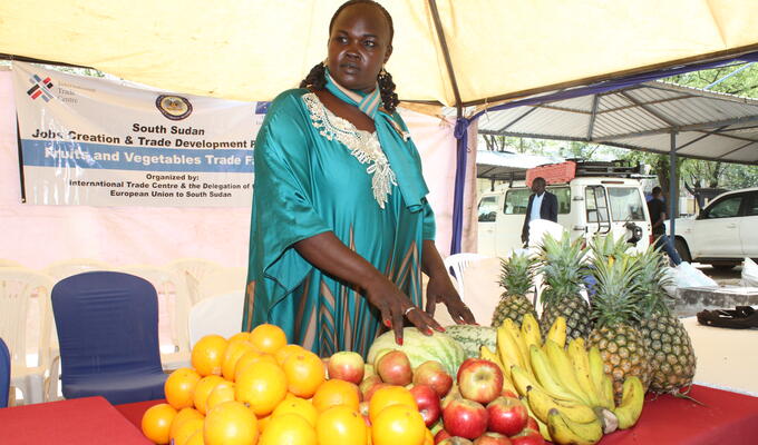 South Sudanese woman stands next to fruit stand
