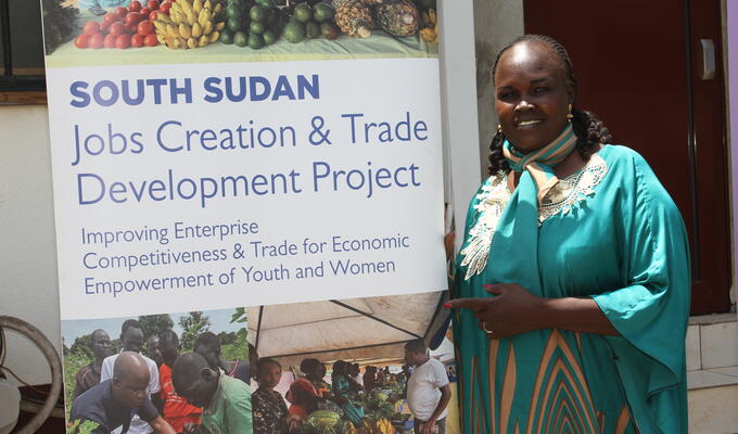 South Sudanese woman stands next to ITC banner