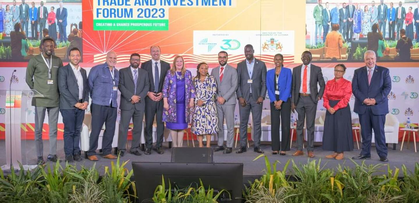 Un groupe de personnes se tient sur la scène devant la bannière du Forum sur le commerce et l'investissement entre l'Afrique et les Caraïbes.