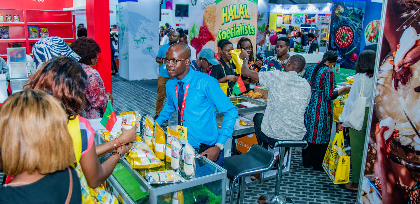 Man in blue shirt presents West African food products at trade fair