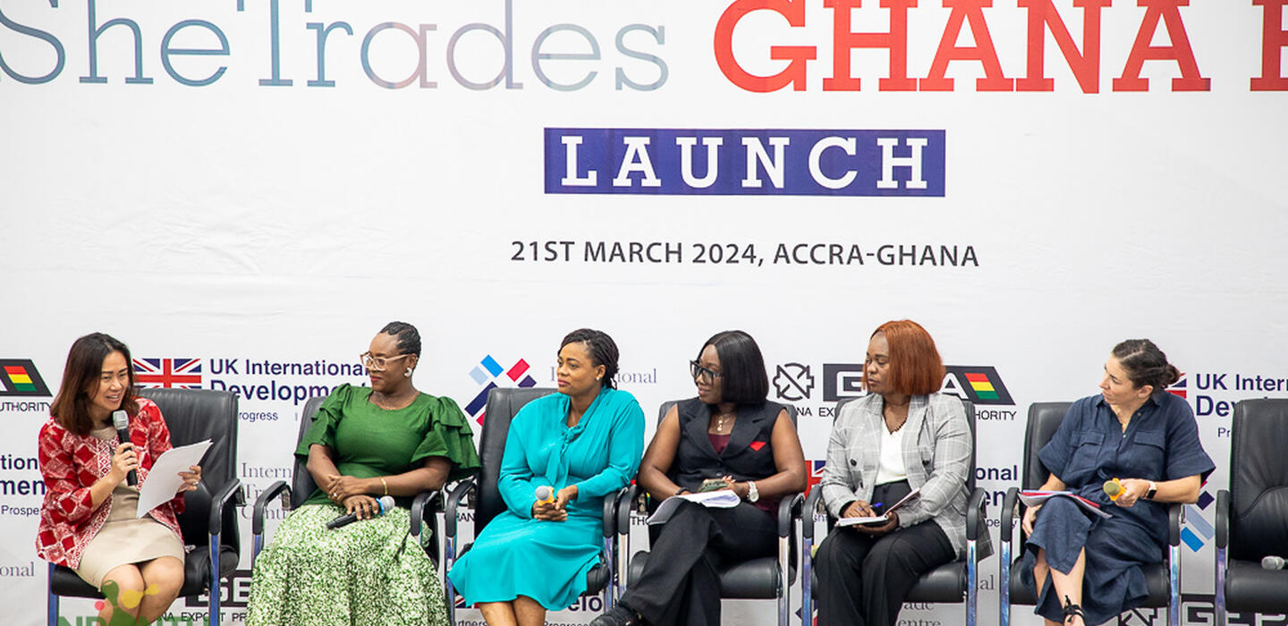 Six women sitting on a stage engaging in a panel discussion. 